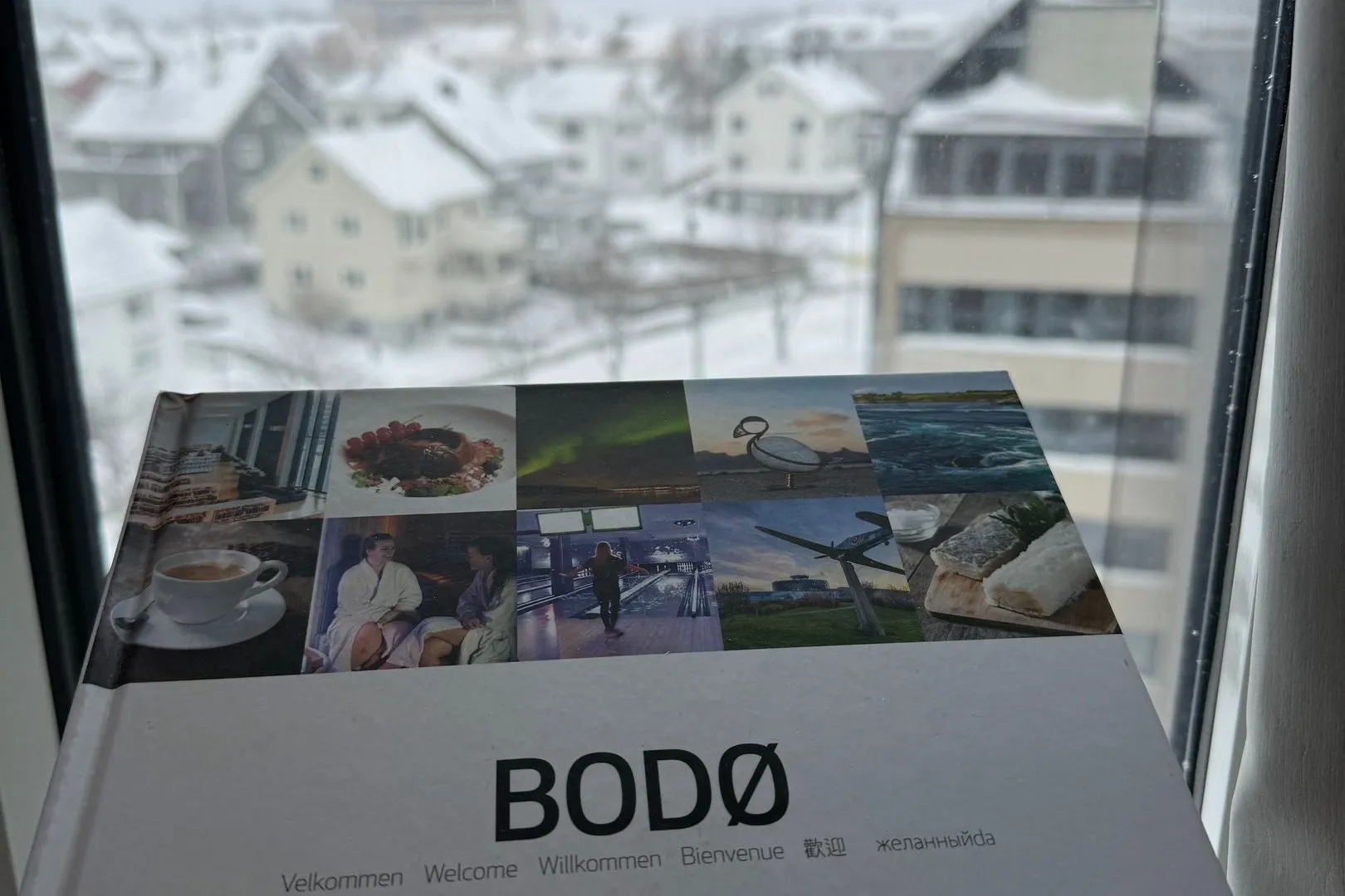 Ein Bodø-Prospekt auf der Fensterbank, draussen die verschneite Stadt