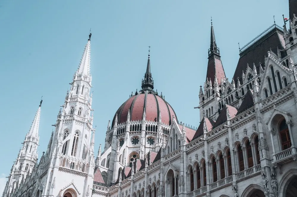 Die rötliche Kuppel und die weissen Spitztürme des Parlamentsgebäudes vor blauem Himmel