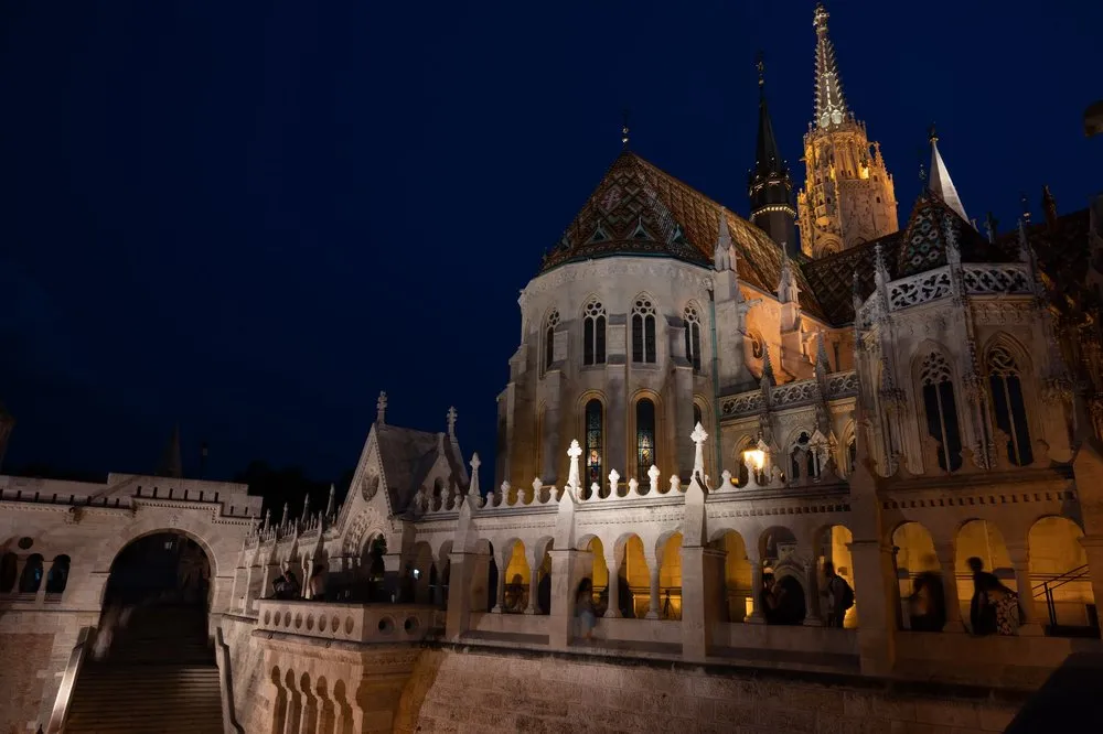 Die Arkaden der Fisherman's Bastion im Abendlicht, dahinter die angestrahlte Kirche, unten links eine Treppe