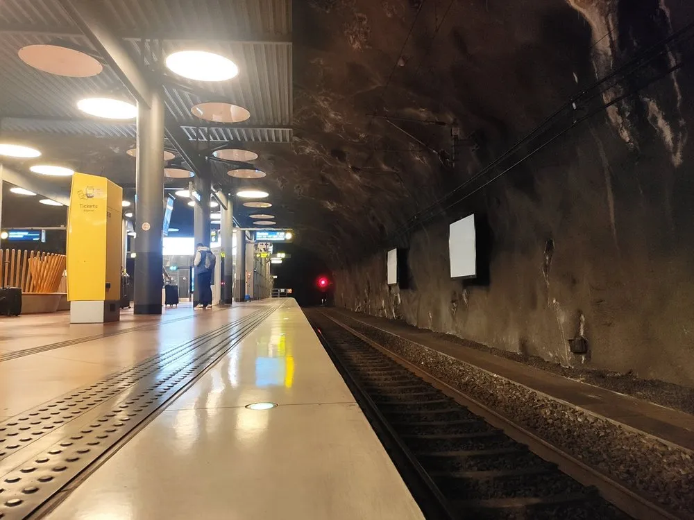 Fast leerer Bahnsteig des Arlanda Express in einem Felstunnel, eine gelbe Säule und im Hintergrund eine Person mit Rucksack