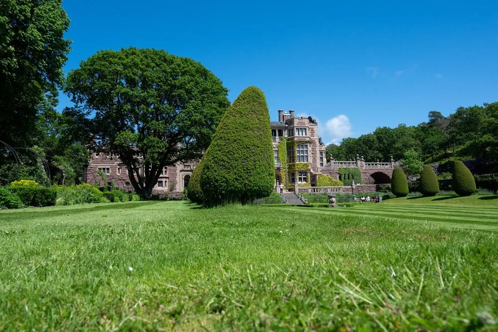 Tjolöholms Slott behind a mown lawn and a cone-shaped trimmed tree