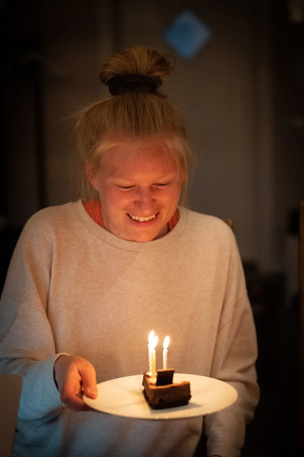 Annina lächelt auf ein Stück Schokoladenkuchen mit brennenden Kerzen hinunter