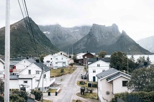 Die Dorfstrasse von Husøy zwischen weissen Häusern, dahinter spitze Berge