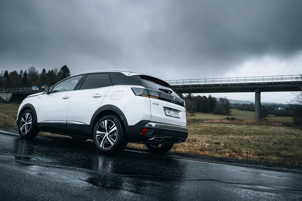 Unser weisses Auto am nassen Strassenrand, im Hintergrund eine Brücke und tiefe graue Wolken