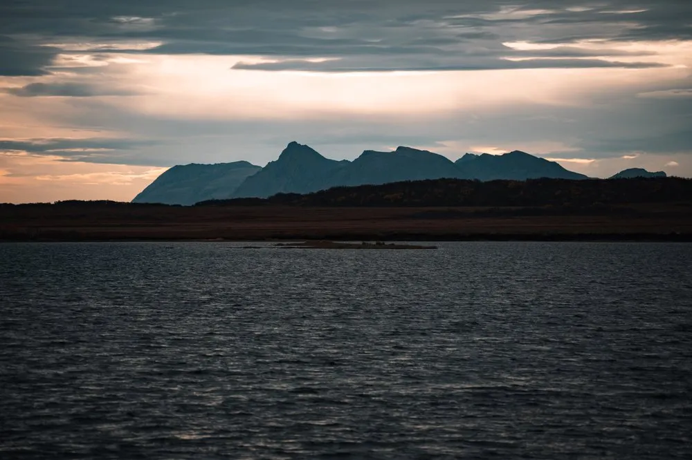 Dunkle Bergsilhouetten über dem Wasser im Morgenlicht, auf der Fahrt von Nøss nach Andenes