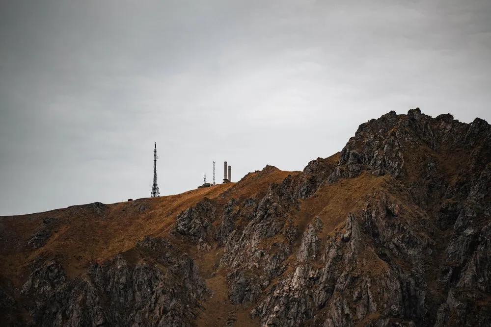 Antennenmasten auf einem felsigen Grat über Bleik unter grauem Himmel
