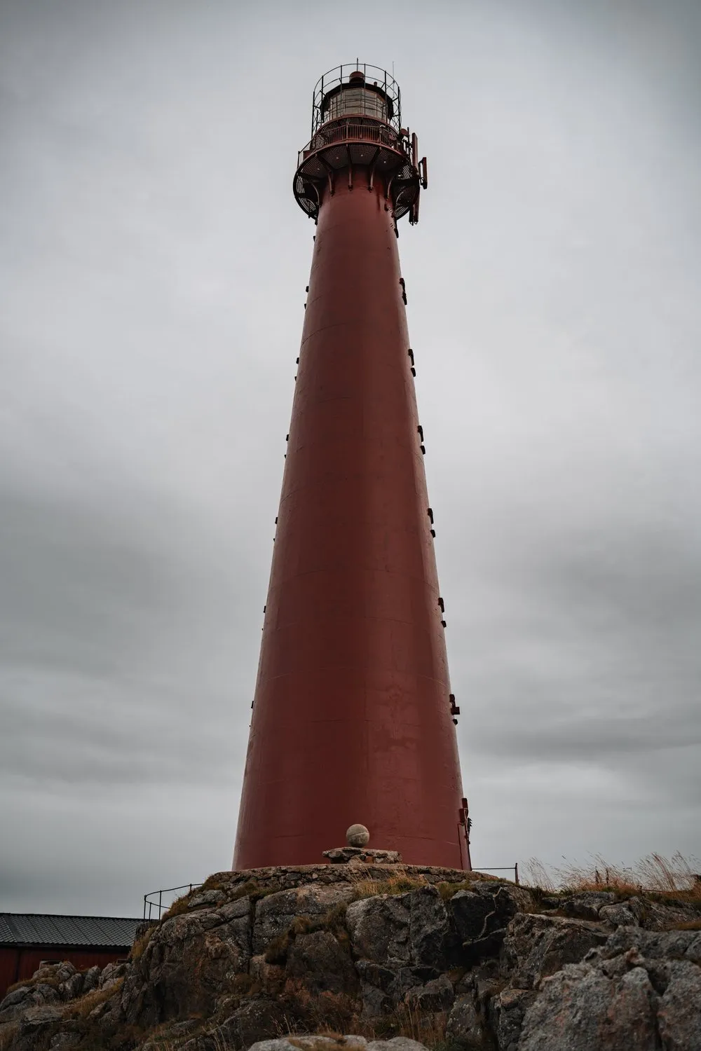 Der rote Leuchtturm von Andenes von unten gegen den grauen Himmel