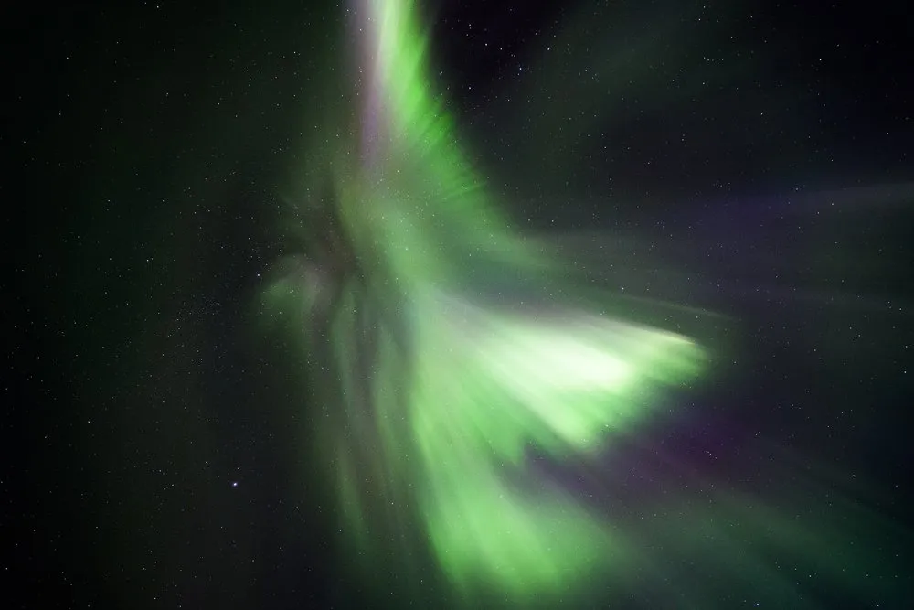 Ein Nordlicht als grüner Strahlenwirbel vor dem Sternenhimmel