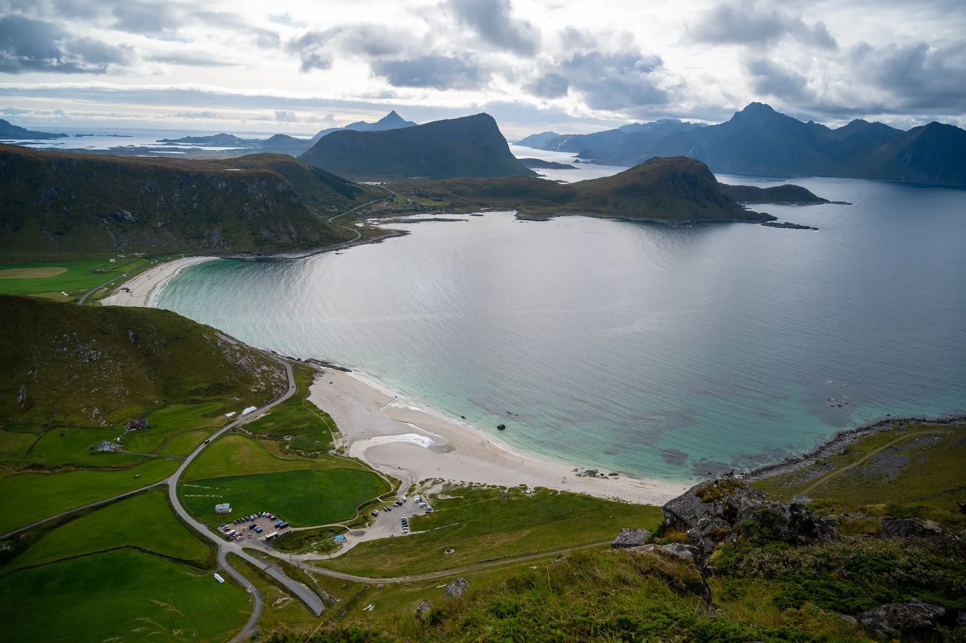 Blick vom Mannen auf den Hauklandstranda mit Strasse und Parkplatz, dahinter Meer und Berge