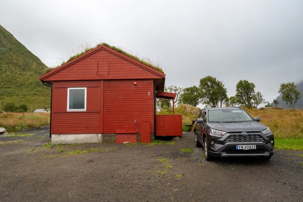 Rotes Häuschen mit Grasdach auf dem Campingplatz in Rystad, davor unser grauer Toyota RAV4