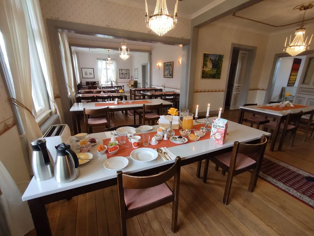 Gedeckter Frühstückstisch im Dining Room der Villa mit Kerzen und Kronleuchtern, im Hintergrund weitere Tische