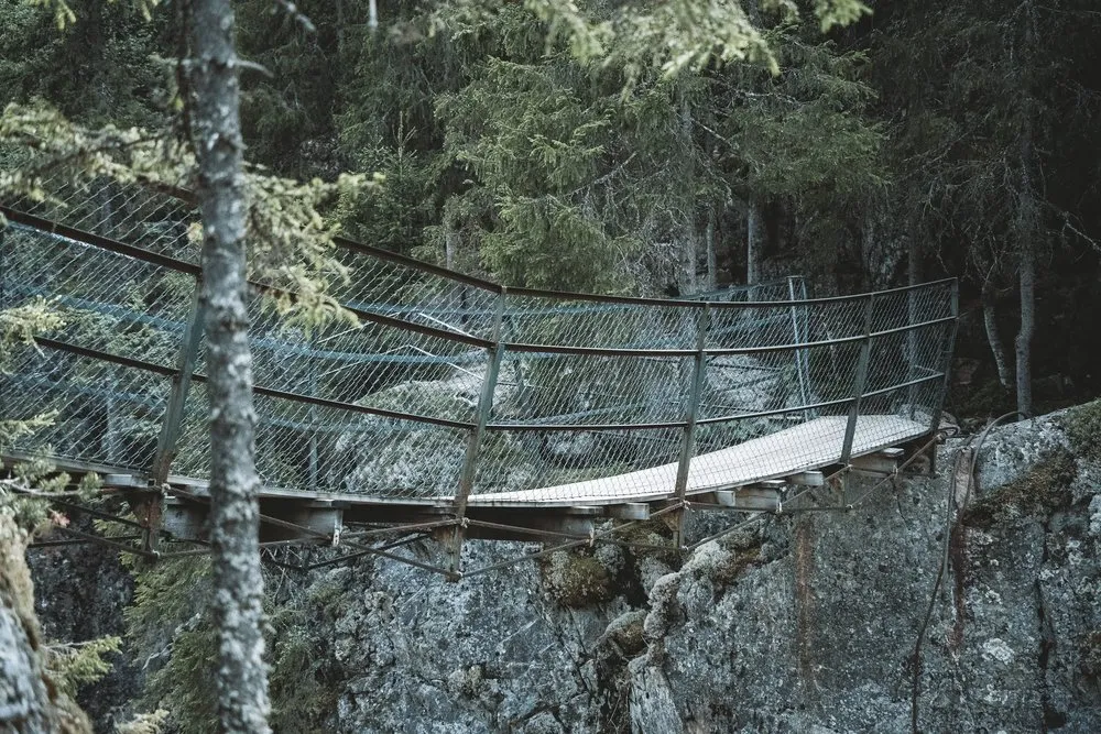 Hängebrücke mit Gitternetz als Geländer über der Schlucht am Helvetesfallet