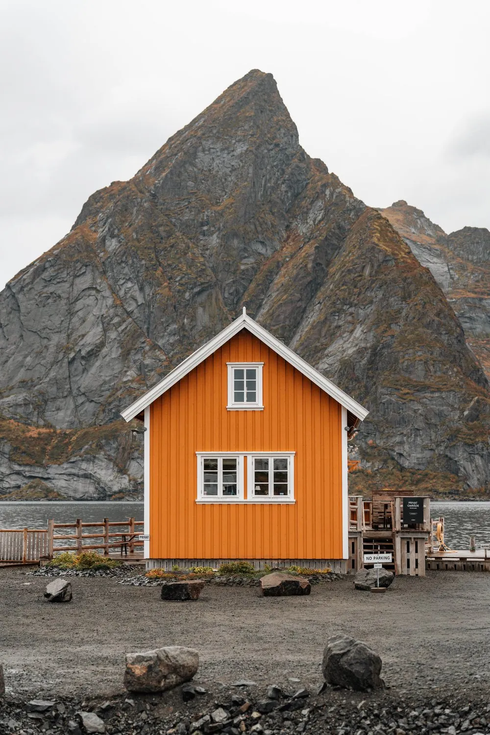 Ein ockerfarbenes Haus mit weissen Fenstern in Sakrisøy vor dem spitzen Olstind
