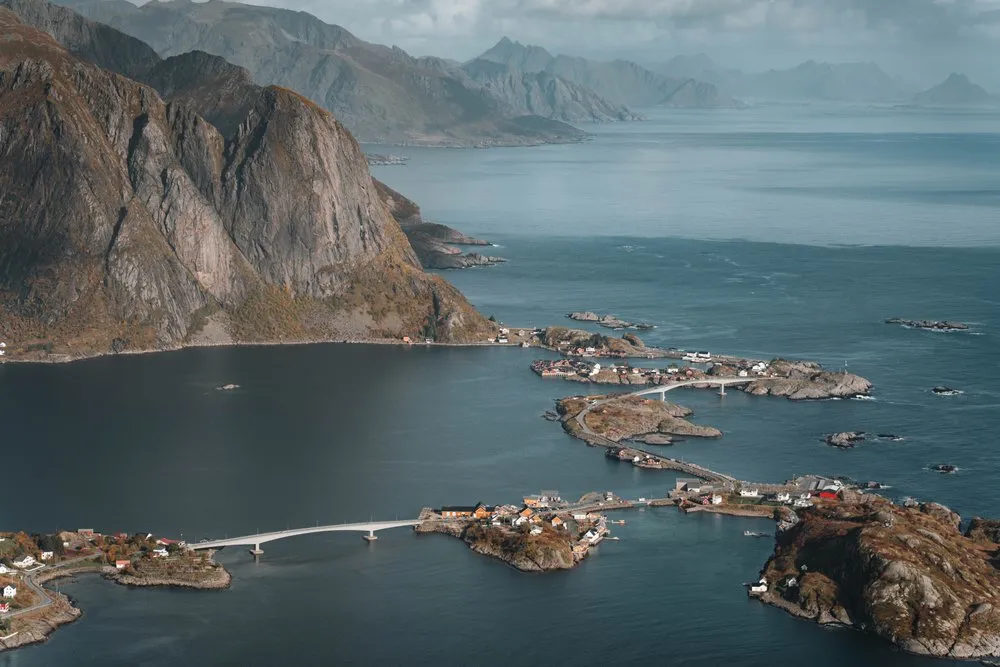 Blick vom Reinebringen auf Reine, die kleinen Inseln und die Brücken im Fjord, links ein steiler Felsberg