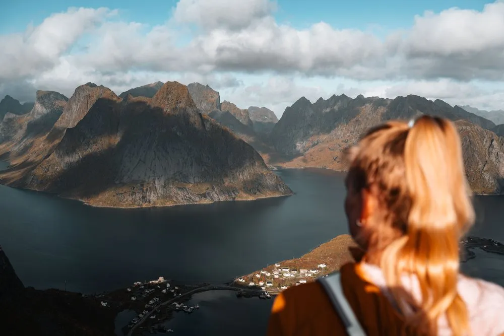Annina mit blondem Rossschwanz schaut vom Reinebringen auf die Berge und den Fjord bei Reine