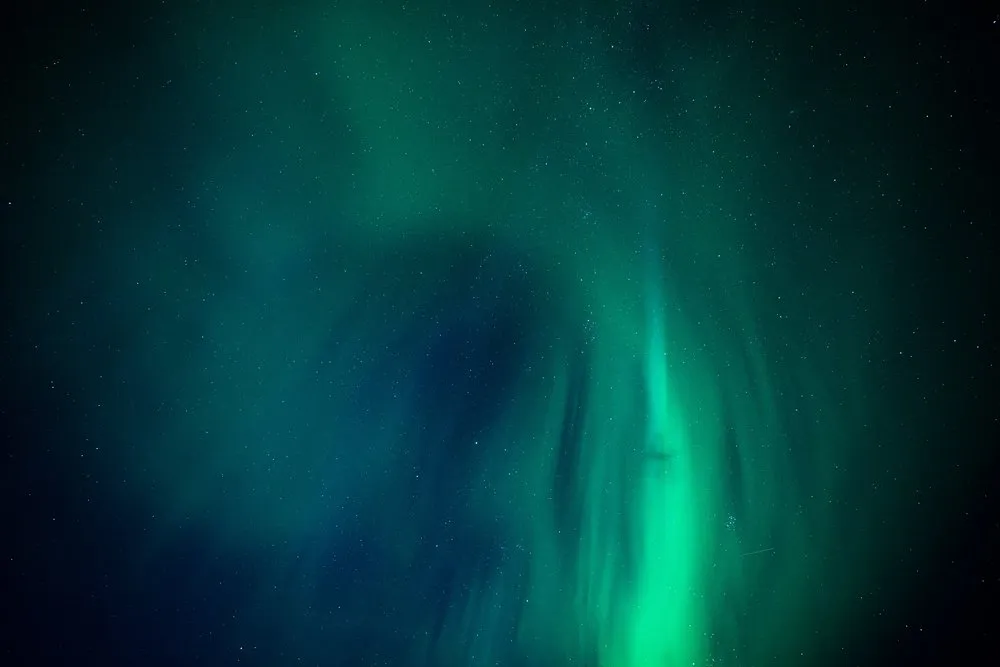 Grünes Nordlicht in Schleiern über den ganzen Himmel, dazwischen viele Sterne