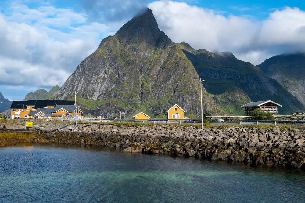Die gelben Häuser von Sakrisøy vor dem Olstind über klarem Wasser