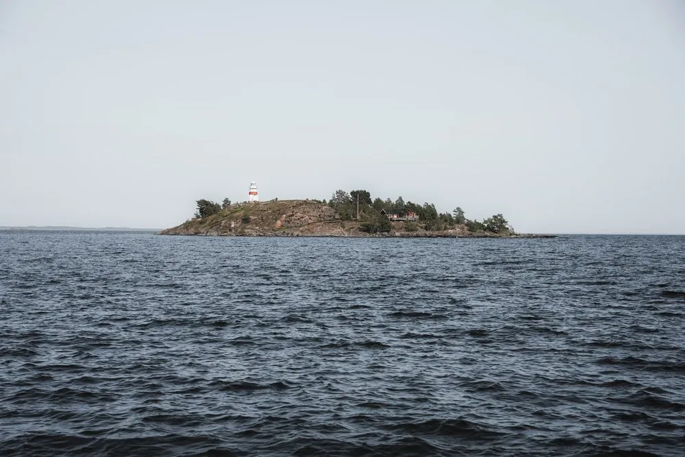 Kleine Insel mit einem rot-weissen Leuchtturm auf dem Vänern