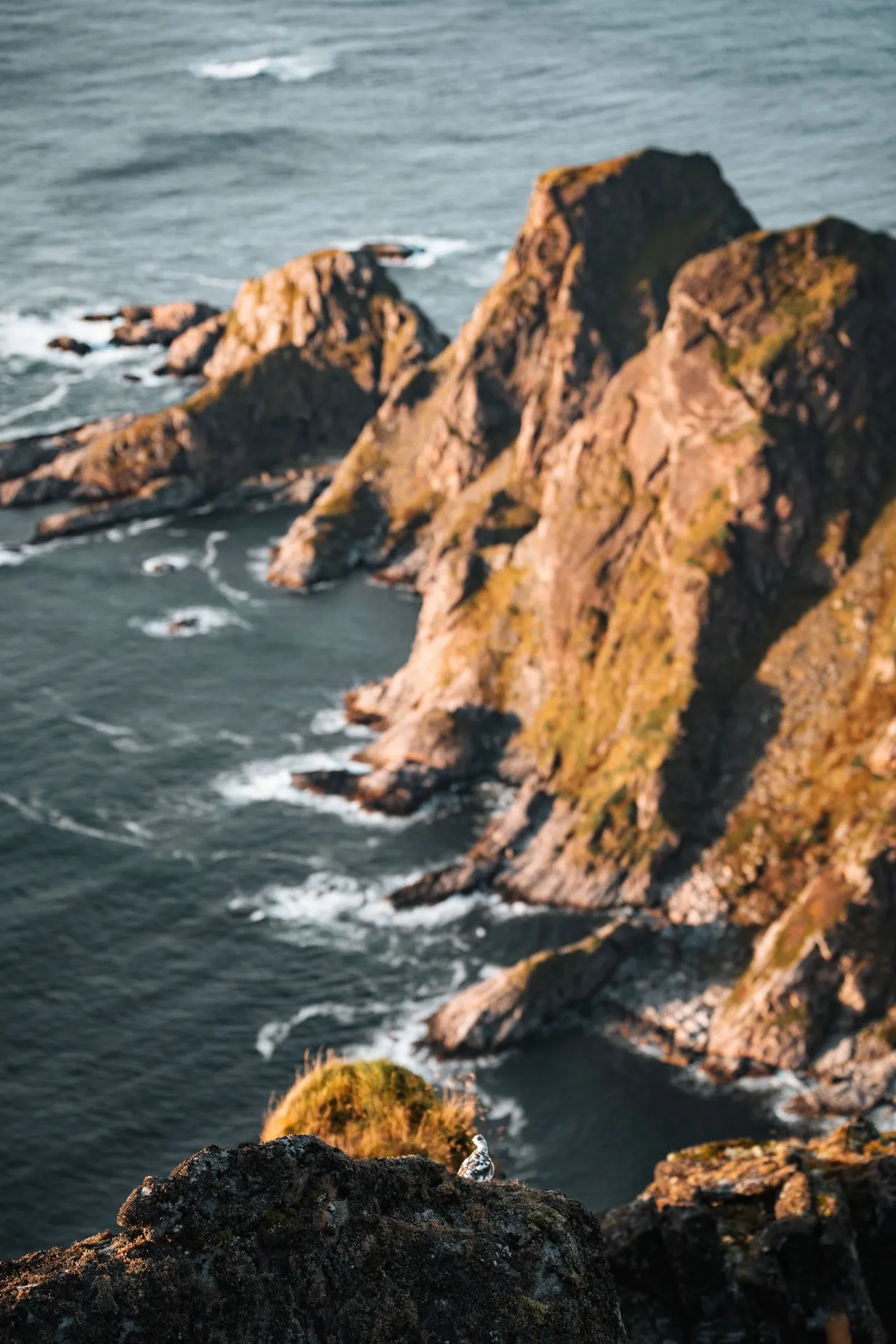 Rugged rocks drop into the surf, seen from Måtind