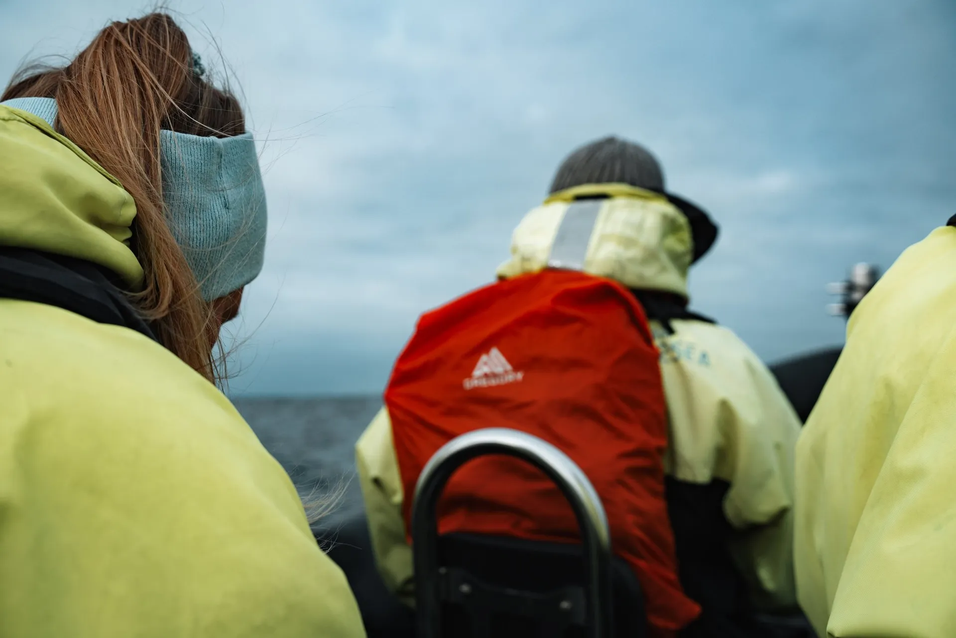 Annina and other passengers in neon yellow thermal suits on the seats of the RIB boat off Andenes, one with a red backpack