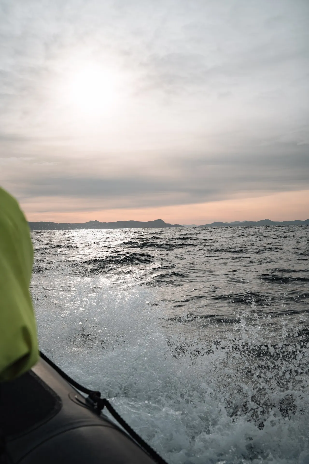 Spray shoots up beside the RIB boat, the sea off Andenes glitters against the light