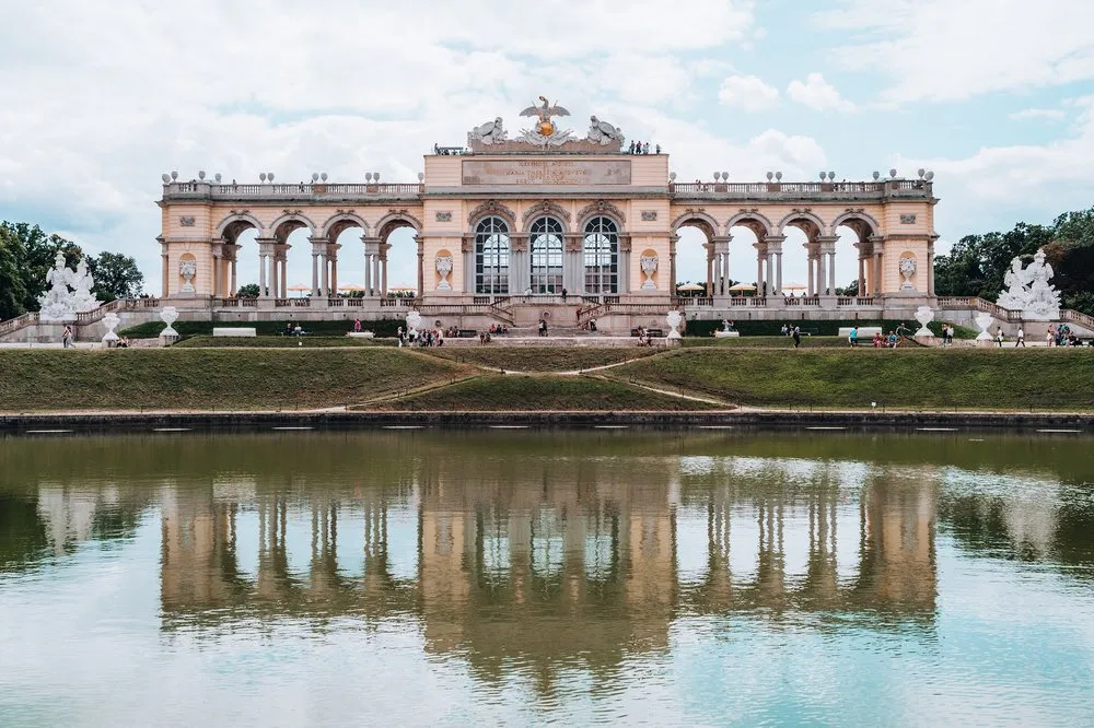 Die Gloriette mit ihren Bögen und weissen Statuen, im Wasserbecken davor gespiegelt