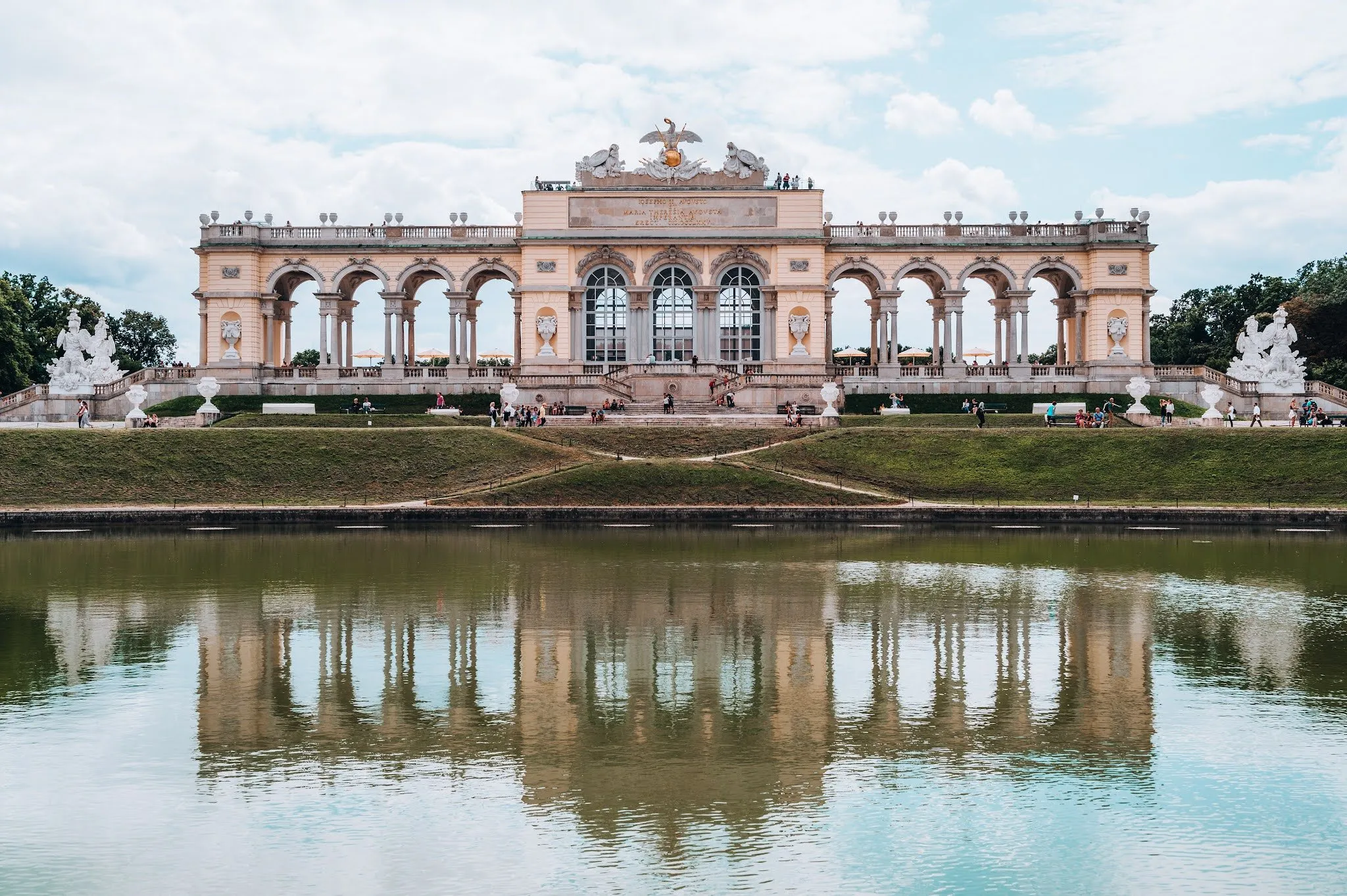 Die Gloriette mit ihren Bögen und weissen Statuen, im Wasserbecken davor gespiegelt